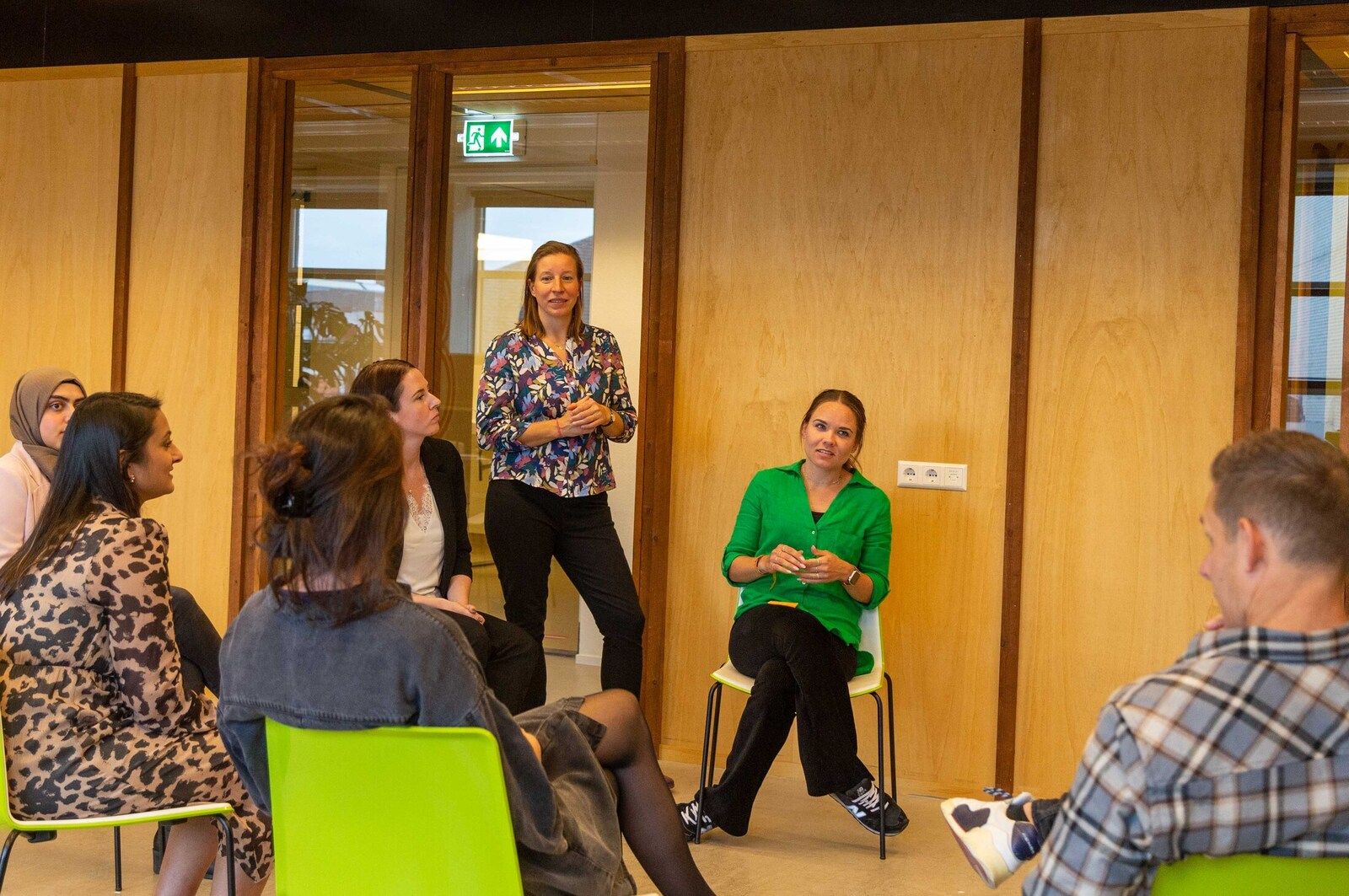 2 personen aan vergadertafel overleggen met 3 personen op een groot scherm